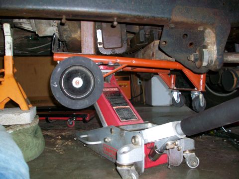1979 Ford Bronco - Undercarriage of a vehicle being supported by jack stands and a floor jack.