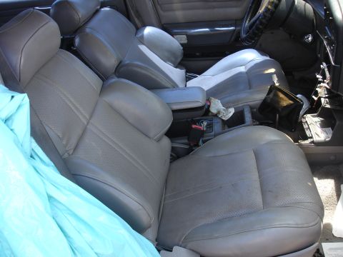 1993 Ford Taurus - The interior of a car shows worn leather seats and a cluttered center console area.