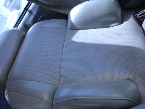 1993 Ford Taurus - Close-up of a perforated light gray leather car seat, showing the texture and stitching.