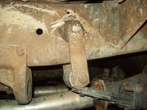 1971 Ford F-100 - Close-up view of the underbody suspension components and frame of a vehicle, showing signs of rust and wear.