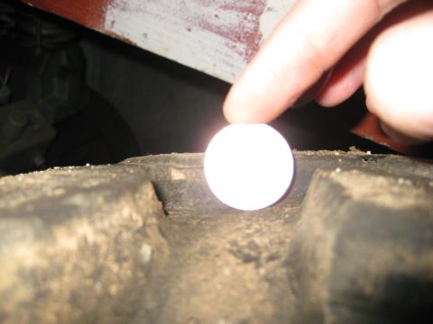 1986 Ford Bronco - A finger is positioned over a section of a tire's tread, obscuring a small white object.