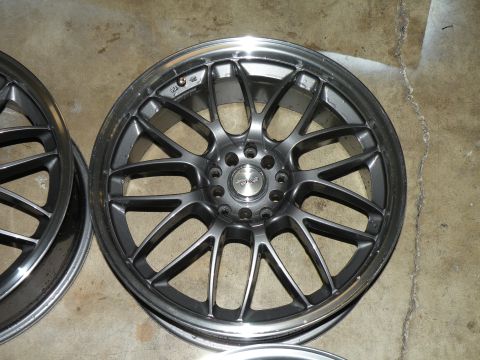 1998 Subaru Legacy - A single dark gray multi-spoke alloy wheel with a silver lip is shown, with another wheel partially visible to the left.