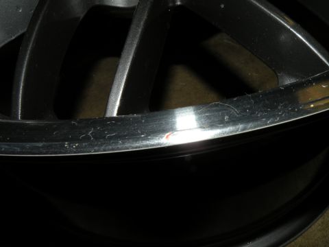 1998 Subaru Legacy - A close-up view of a damaged alloy wheel rim, showing scuffs and a small paint chip.