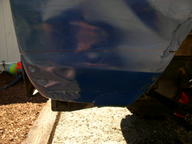 Close-up of a blue boat hull with visible scratches and a small dent near the bottom edge