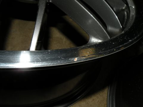 1998 Subaru Legacy - Close-up view of a damaged alloy wheel rim, showing scratches and a chip on the outer edge.