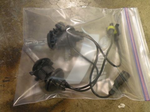 1998 Subaru Legacy - Two headlight bulbs are shown inside a clear plastic bag on a concrete surface.