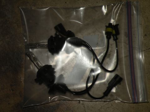 1998 Subaru Legacy - Bagged HID headlight bulbs and wiring connectors on a concrete surface.