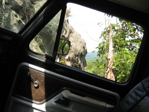 1978 Ford Bronco - Looking out the window of a vehicle at a rocky cliff face and lush green trees.
