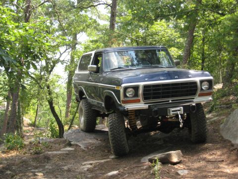 1978 Ford Bronco - This lifted Ford Bronco navigates a rocky path through a dense forest, its off-road capabilities.