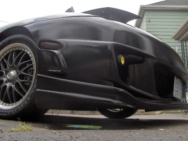 Low front view of a matte black sports car with multi-spoke wheels in a driveway