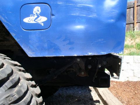 1979 Ford Bronco - Close-up of a blue vehicle's rear quarter panel, showing the gas cap and a decorative sticker.