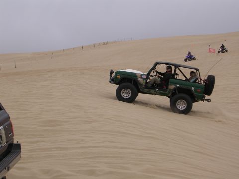 1985 Toyota 4Runner - Off-road vehicles navigate sandy terrain under an overcast sky, with ATVs visible in the distance.
