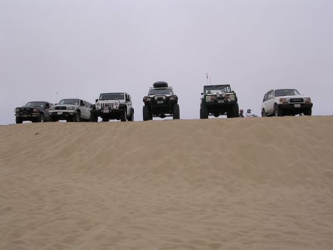 1985 Toyota 4Runner - Several off-road vehicles are lined up on a sandy hill.