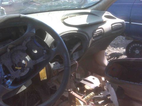 1995 Ford Bronco - The interior of a damaged vehicle shows a broken dashboard and steering wheel, with another car in the background.