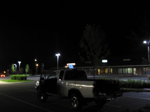 2001 Ford Crown Victoria - A pickup truck is parked in a lot at night with its driver's door open.