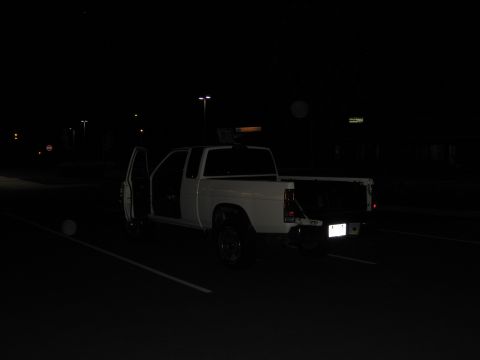 2001 Ford Crown Victoria - A white pickup truck is parked with its doors open in a dimly lit parking lot at night.