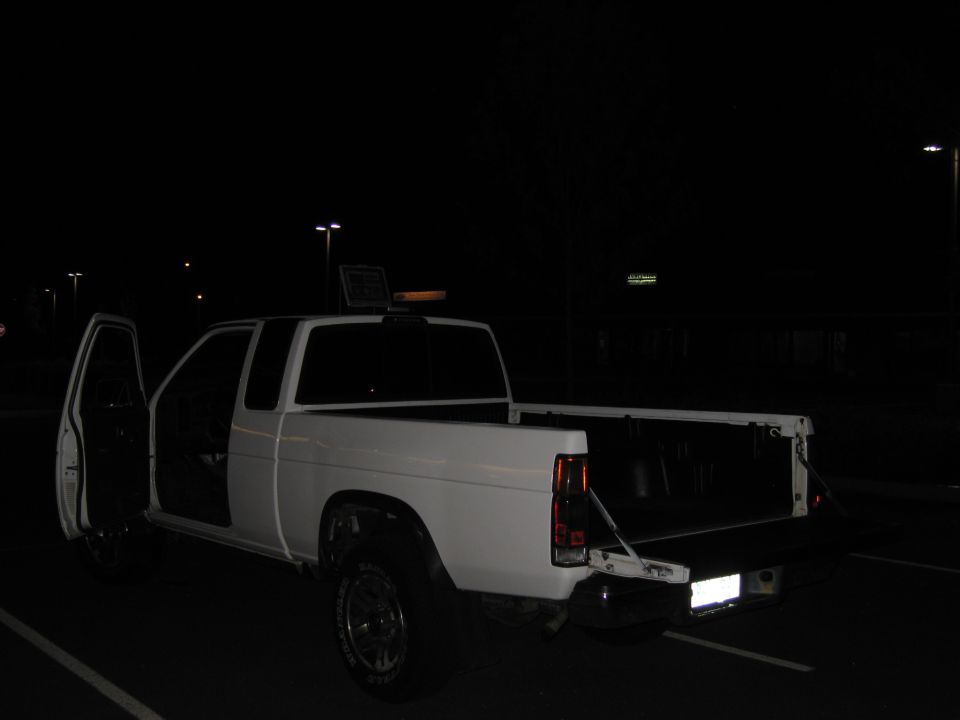 White pickup truck with doors open and tailgate down, parked at night