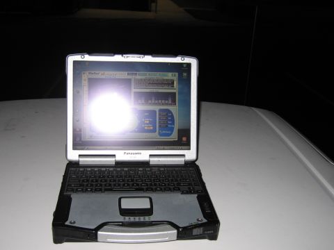 2001 Ford Crown Victoria - A Panasonic Toughbook laptop is placed on the hood of a white vehicle in the dark.