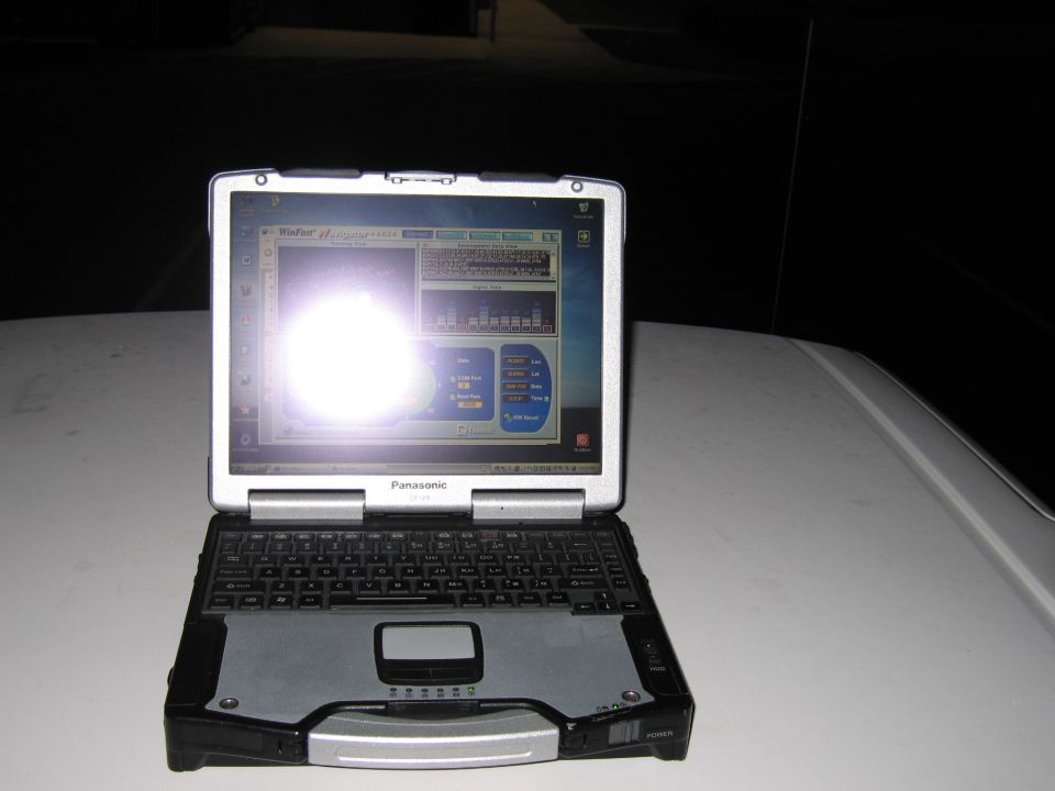 Panasonic Toughbook laptop on a white car hood at night