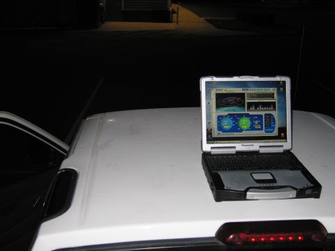 2001 Ford Crown Victoria - A laptop displaying GPS software sits on the roof of a white vehicle at night.