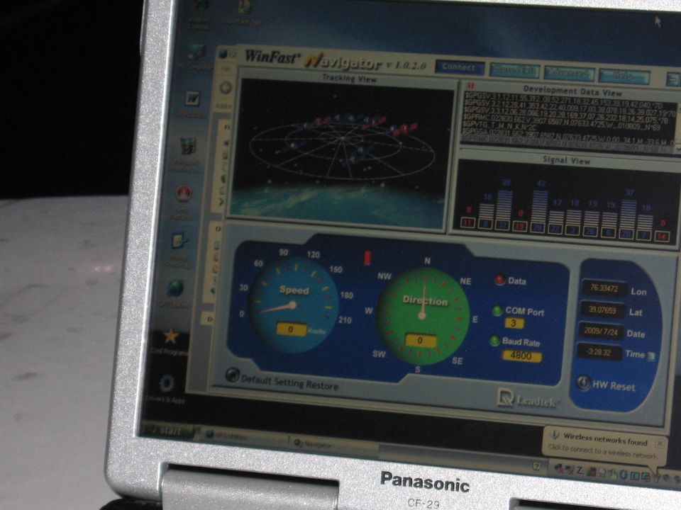 Laptop screen shows WinFast Navigator GPS software with speed and direction gauges, satellite tracking view, and development data