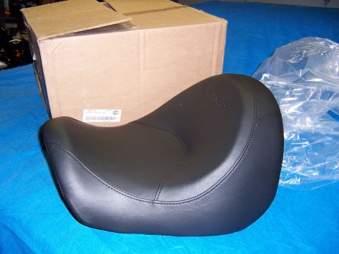 1987 Ford Bronco - A black motorcycle seat is shown in front of a cardboard box, with plastic packaging to the right.