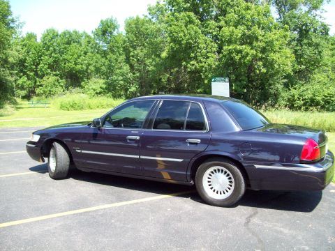1999 Mercury Grand Marquis - Side view of a dark purple sedan parked in a lot.