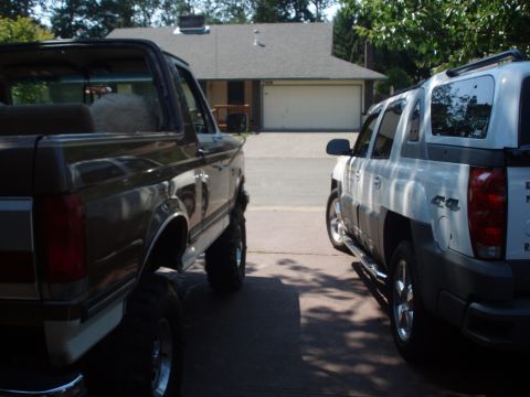 1990 Ford Bronco - A dark brown Ford Bronco and a white Chevrolet Avalanche are parked in a driveway in front of a house.