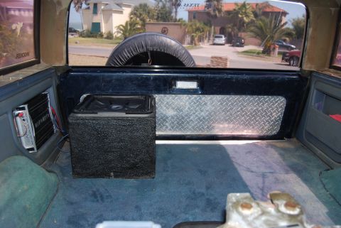 1991 Ford Bronco - The interior of the vehicle shows a subwoofer and amplifier, with a spare tire visible through the rear window.