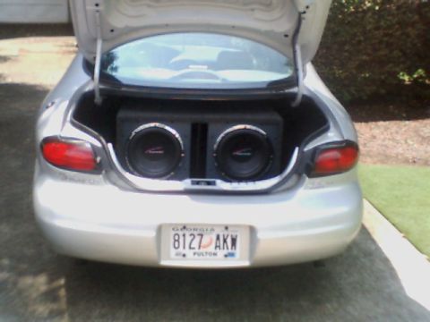 1998 Ford Taurus - The trunk of a silver sedan is open, revealing a large subwoofer enclosure with two speakers inside.