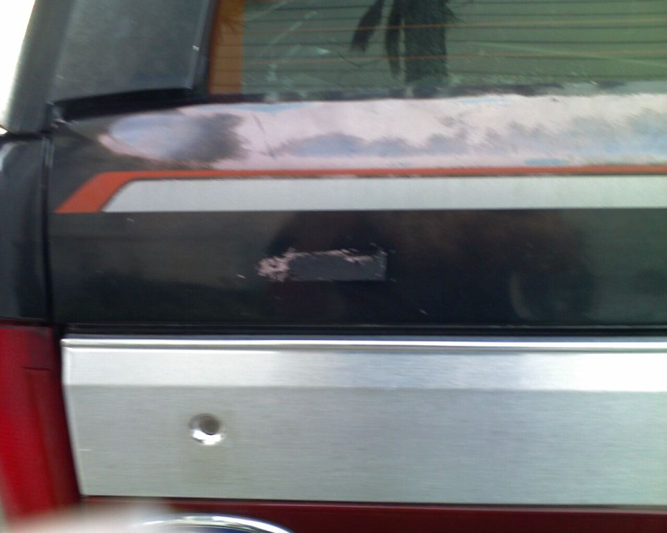 Close-up of Bronco tailgate with black trim, removed emblem spot, and brushed metal panel with lock keyhole