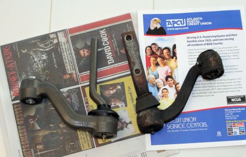 1976 Ford Ranchero - Two suspension control arms are displayed on top of newspapers and an Atlanta Postal Credit Union flyer.