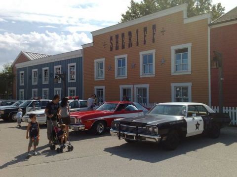 1991 Ford LTD Crown Victoria - A vintage police car is parked in front of a sheriff's building, with other vehicles and people nearby.