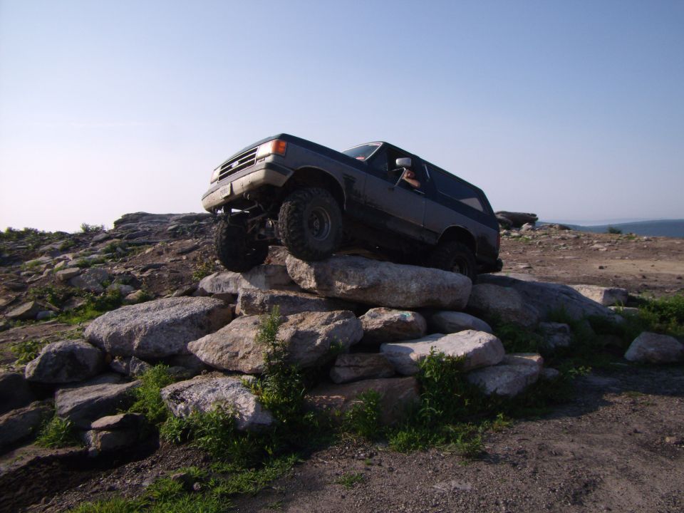 SUV climbing over large rocks on a trail