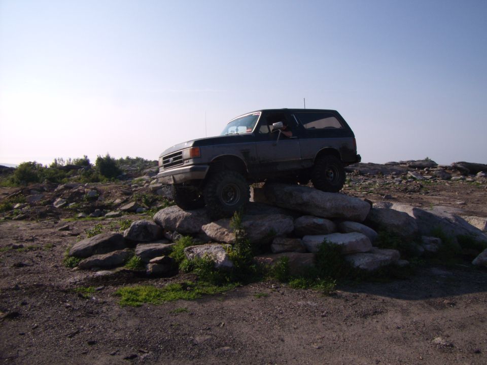Dark gray Ford Bronco with off-road tires climbing over rocks
