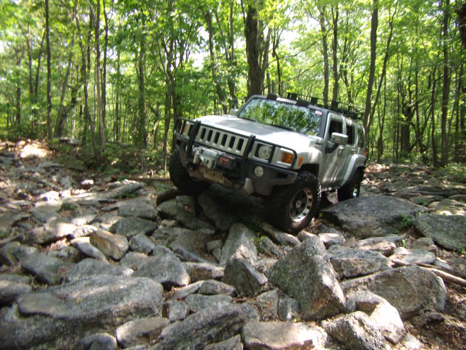 Hummer H3 navigating a rocky trail in a forest