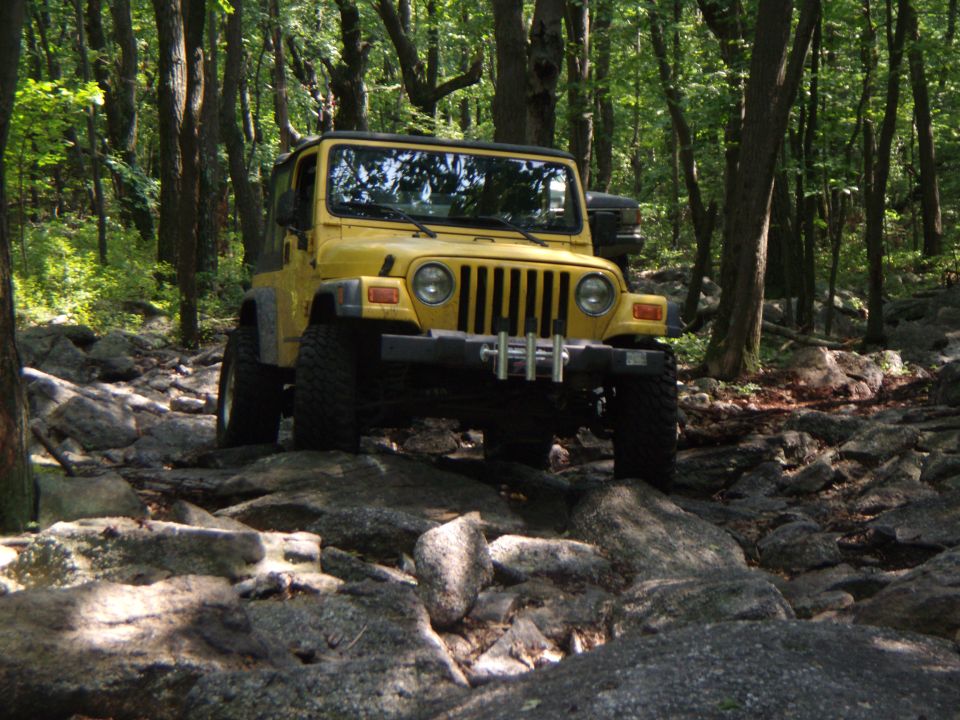 Yellow 2003 Jeep Wrangler navigating a rocky trail