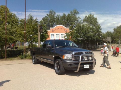 1991 Ford LTD Crown Victoria - A dark gray Dodge Ram pickup truck is parked in front of a building that appears to be part of a themed attraction.