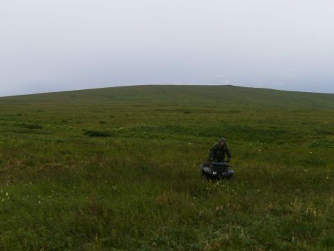 2000 Ford E350 - ATV rider traverses a vast, grassy landscape under an overcast sky.