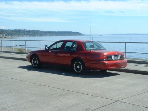 1999 Ford Crown Victoria - Red Ford Crown Victoria parked by the water on a sunny day.