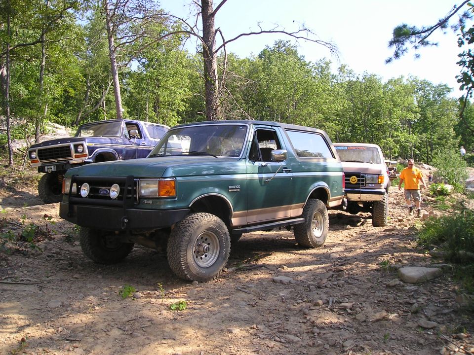 Green Ford Bronco with tan stripe, off-road tires, and aftermarket bumper