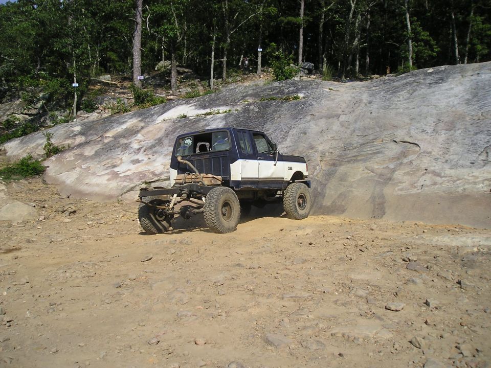 1989 Ford Bronco off-roading, rear chassis exposed, dark blue and white