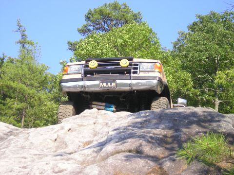 1989 Ford Bronco - This 1989 Ford Bronco is shown from the front, navigating a rocky terrain with decorative smiley face lights.