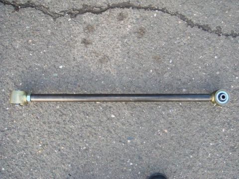1979 Ford Bronco - A single suspension component, likely a radius arm or track bar, is shown lying on a cracked asphalt surface.