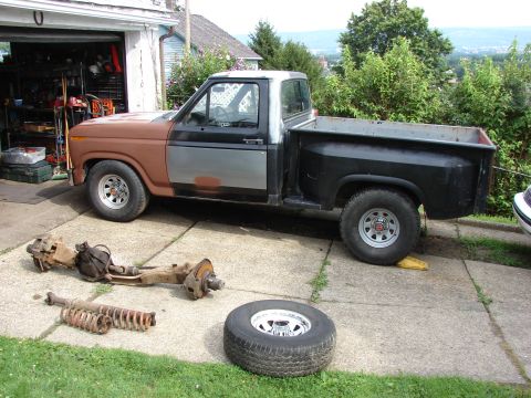 1985 Ford F-150 - Ford F-150 pickup truck with front suspension components laid out on the driveway.