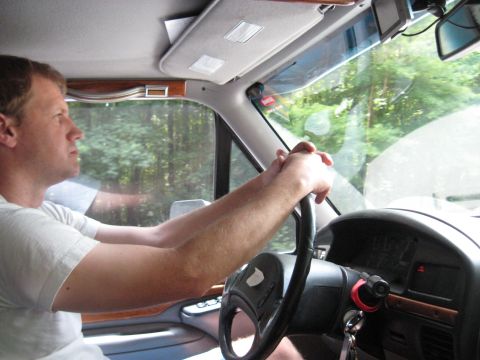 1978 Ford Bronco - Interior view of a man driving a vehicle, with trees seen through the windshield.