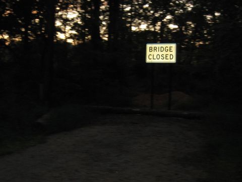 1978 Ford Bronco - A sign indicates a bridge closure in a dark, wooded setting at sunset.