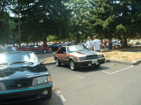 1999 Ford Crown Victoria - A vintage Ford Mustang is displayed at an outdoor car show with other vehicles present.