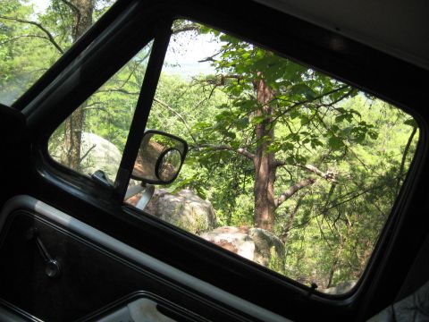 1978 Ford Bronco - View from the driver's seat of a 1978 Ford Bronco looking out at a rocky, wooded landscape.