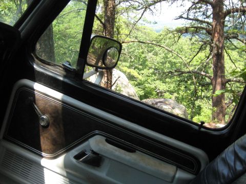 1978 Ford Bronco - Looking out the passenger side window of a vehicle parked in a wooded area with a scenic overlook.